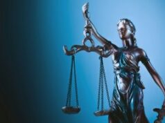 CFTC Sues Wisconsin in Escalating Fight Over Prediction Market Regulation A statue of Lady Justice holding scales in front of a blue background.