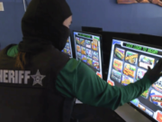 Florida authorities bust Manatee County illegal gambling network during enforcement operation Florida sheriff investigator examines illegal gambling slot machines during Manatee County arcade enforcement raid and statewide Florida gaming crackdown