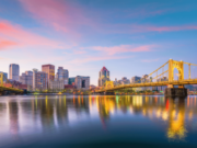 Pennsylvania regulators approve $180K in gaming fines while expanding involuntary exclusion lists Pittsburgh skyline at sunset with illuminated yellow bridges reflecting across the Allegheny River in downtown Pennsylvania. Pennsylvania regulators approve $180K in gaming fines while expanding involuntary exclusion lists