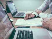 UK gambling reforms may hurt economy less than industry warnings suggest, study finds Two people studying paperwork on a desk with laptops.