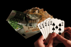 University researchers launch major independent UK gambling harms evidence center Person holding royal flush poker hand beside euro banknotes and luxury watch symbolizing gambling winnings, casino betting, and financial risk. University researchers launch major independent UK gambling harms evidence center
