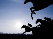 Hawthorne creditors seek probe into racing funds amid bankruptcy dispute case Silhouetted jockeys ride racehorses over a steeplechase jump during a horse racing event, illustrating thoroughbred racing and equestrian sport against a dramatic sky. Hawthorne creditors seek probe into racing funds amid bankruptcy dispute case
